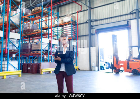 Female manager writing on clipboard in warehouse Stock Photo