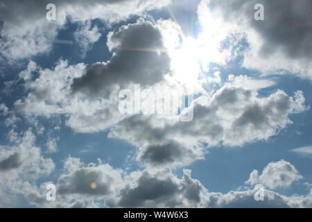 Bright blue sky, with sun coming through white clouds Stock Photo