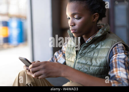 Female worker using mobile phone in warehouse Stock Photo