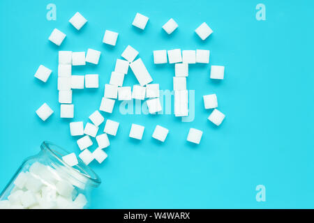 Cubes of sugar on a blue background. "Fat" text from sugar cubes. Top view Stock Photo