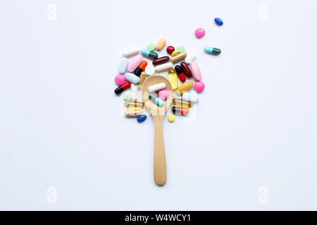 Colorful tablets, capsules and pills with wooden spoon on white background. Stock Photo