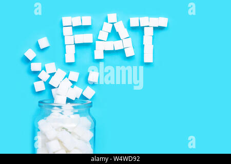 Cubes of sugar on a blue background. "Fat" text from sugar cubes. Top view Stock Photo