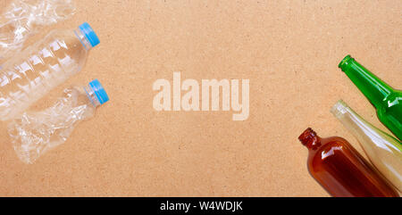 Plastic bottles with glass bottles on plywood background. Copy space Stock Photo