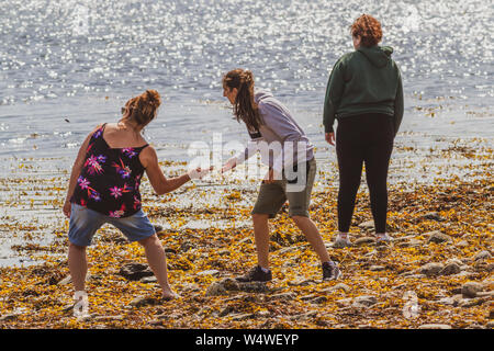 Family enjoying stone skimming on a beach in Scotland Stock Photo