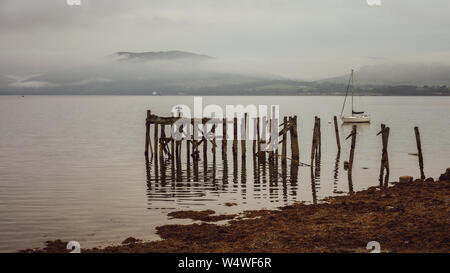 The old, ruined wooden pier with mountains behind on a misty day - Port Bannatyne, Isle of Bute, Scotland