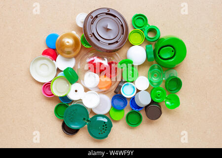 Colorful plastic bottle caps and plastic glass lid on plywood background. Stock Photo