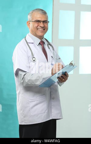 Male doctor writing prescription and smiling Stock Photo