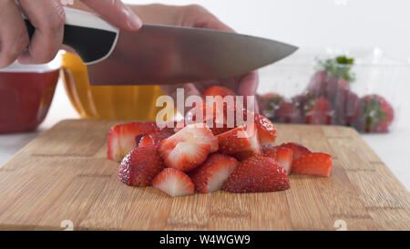 Strawberry Slices on a Wooden Chopping Board Close Up. Woman Slicing Strawberries. Fruit Salad, Dessert. Stock Photo