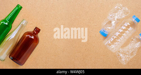 Glass bottles with plastic bottles on plywood background. Copy space Stock Photo