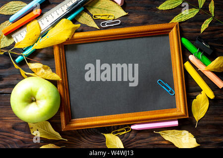 Frame Background Back to school. Table with autumn leaves, note pad, apple  and school supplies. Free space for your text. Stock Photo