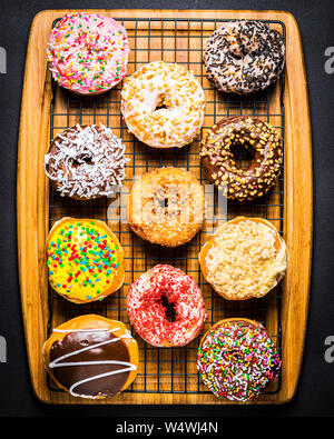 assorted donuts on wire rack on wooden cutting board Stock Photo