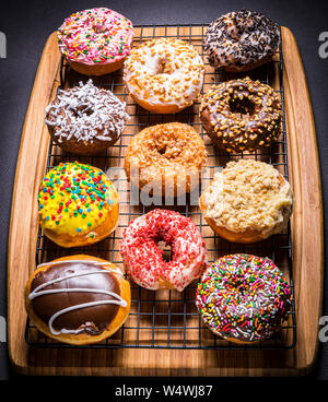 assorted donuts on wire rack on wooden cutting board Stock Photo