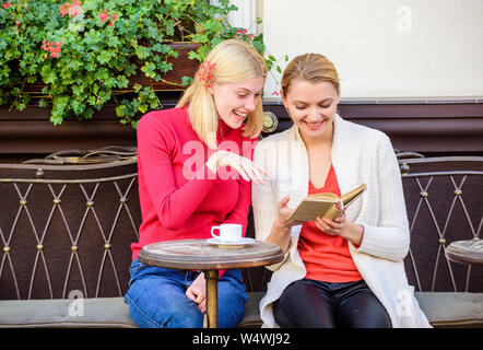 Reading inspiring book. Self improvement and education. Discussing popular bestseller book. Book every girl should read. Girls friends sitting cafe terrace drinking coffee. Female literature. Stock Photo