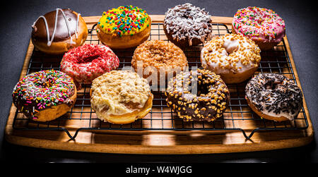 assorted donuts on wire rack on wooden cutting board Stock Photo