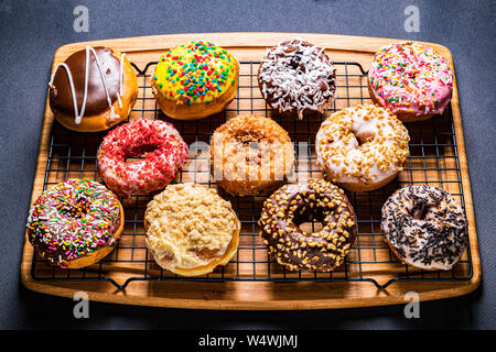 assorted donuts on wire rack on wooden cutting board Stock Photo