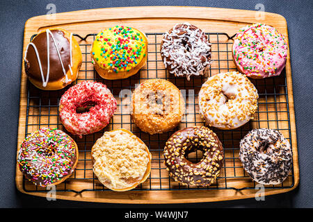 assorted donuts on wire rack on wooden cutting board Stock Photo