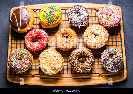 assorted donuts on wire rack on wooden cutting board Stock Photo