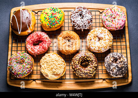assorted donuts on wire rack on wooden cutting board Stock Photo
