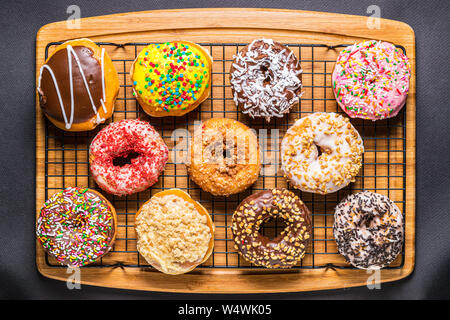 assorted donuts on wire rack on wooden cutting board Stock Photo