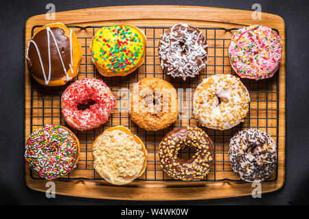 assorted donuts on wire rack on wooden cutting board Stock Photo