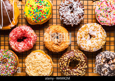 assorted donuts on wire rack on wooden cutting board Stock Photo