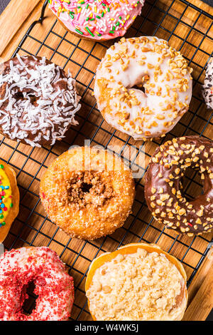 assorted donuts on wire rack on wooden cutting board Stock Photo