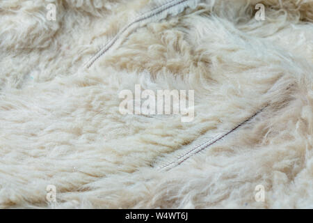 Old white sheep fur lining closeup background with selective focus and blur. Stock Photo