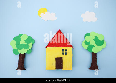 Hand made yellow house and trees on blue background Stock Photo