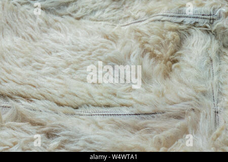 Old white sheep fur lining closeup background with selective focus and blur. Stock Photo