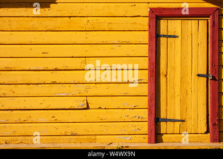 Yellow and red wooden background of peeling cracked surface. Abstract pattern in rustic style with door Stock Photo
