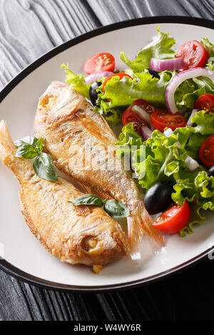 fried pink dorado served with lemon and fresh vegetables close-up on a plate on the table. vertical Stock Photo