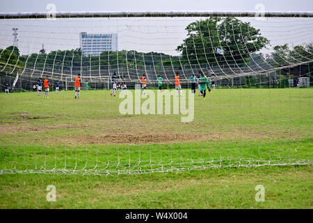 Boys are playing soccer in soccer field, Picture is captured behind soccer goal. Stock Photo