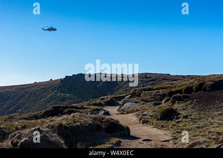 HM Coastguard search and rescue helicopter above the Kinder Scout plateau, Edale, Peak District, Derbyshire, England, UK Stock Photo