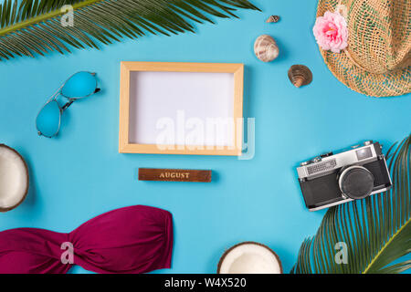 Photo frame, hat, camera, sunglasses, coconuts, on the blue background. Top view. Stock Photo