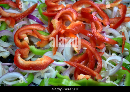non edited photo of fresh sliced raw green and red pepper with onion on plate Stock Photo