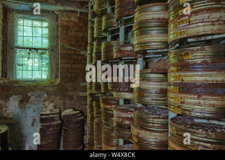 Destroyed from time to time storage room with stored old rusty round boxes with old film Stock Photo