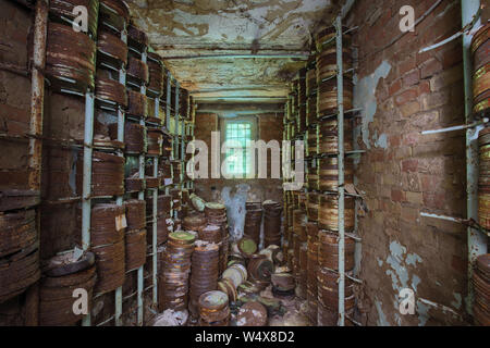 Destroyed from time to time storage room with stored old rusty round boxes with old film Stock Photo