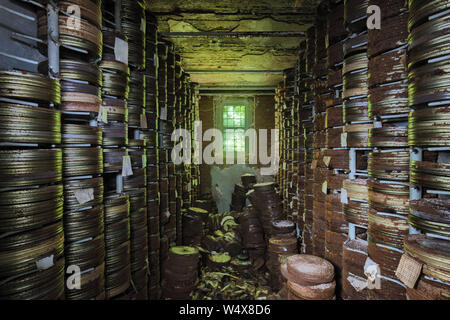 Destroyed from time to time storage room with stored old rusty round boxes with old film Stock Photo