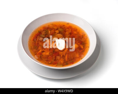 Soup with chicken meat, potatoes, carrot, tomatoes in bowl. Plate of orange red russian-style soup isolated on white. Isolated on white with clipping Stock Photo