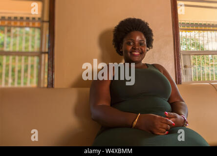 KABALAGALA,UGANDA - APRIL 12,2017: Kenrock hotel A big African woman is sitting on a couch in the foyer of the hotel. Stock Photo