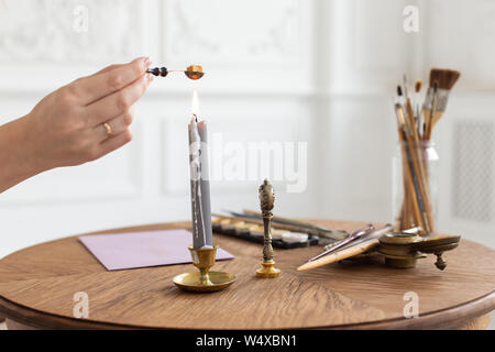 A calligrapher woman makes a wax seal on the envelope. Close-up. Soft focus Stock Photo