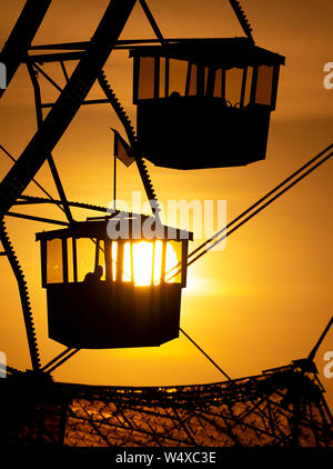 Munich, Germany. 25th July, 2019. The sun sets behind a big wheel in the Olympic Park. Credit: Sven Hoppe/dpa/Alamy Live News Stock Photo