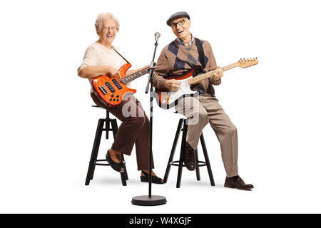 Full length portrait of a senior man and woman sitting and playing electric guitars isolated on white background Stock Photo