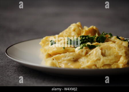 Scrambled eggs on white plate with parsley and butter. Dark and moody food photography. Healthy breakfast, lunch and dinner. Stock Photo