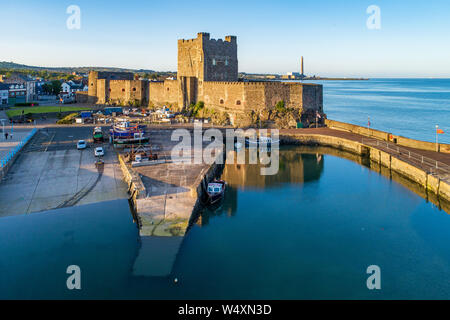 Medieval Norman Castle and harbor with boat ramp and wave breaker in Carrickfergus near Belfast, Northern Ireland, UK. Aerial view  in sunset light. O