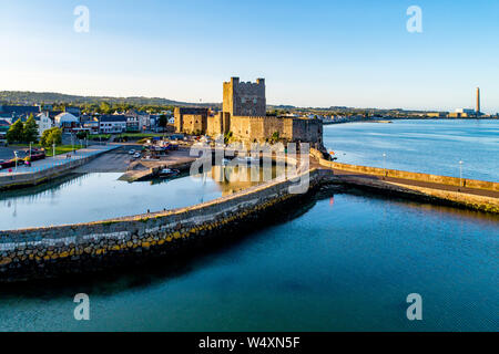 Medieval Norman Castle and harbor with boat ramp and wave breaker in Carrickfergus near Belfast, Northern Ireland, UK. Aerial view  in sunset light. Stock Photo