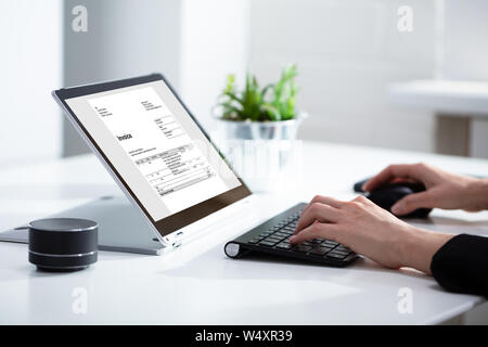 Close-up Of Businesswoman's Hands Working On Invoice On Laptop At Office Stock Photo