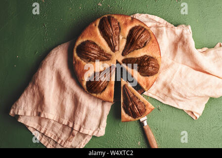 Tasty fruitcake with pears on a kitchen towel. Above view with pear tart on a green table Stock Photo