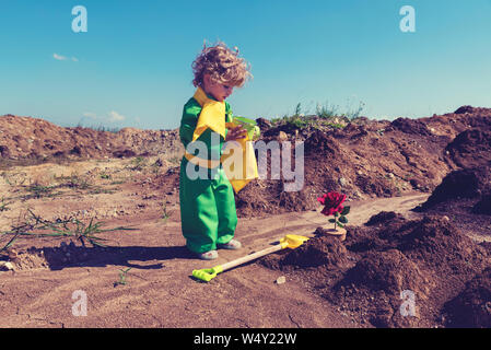 Cute toddler boy with curly blond hair holding green watering can Little prince concept Selective focus Stock Photo