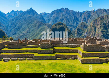 Inca ruin of Machu Picchu with terraced fields and ceremonial buildings, incidental tourists walking on the archaeological site, Cusco Province, Peru. Stock Photo